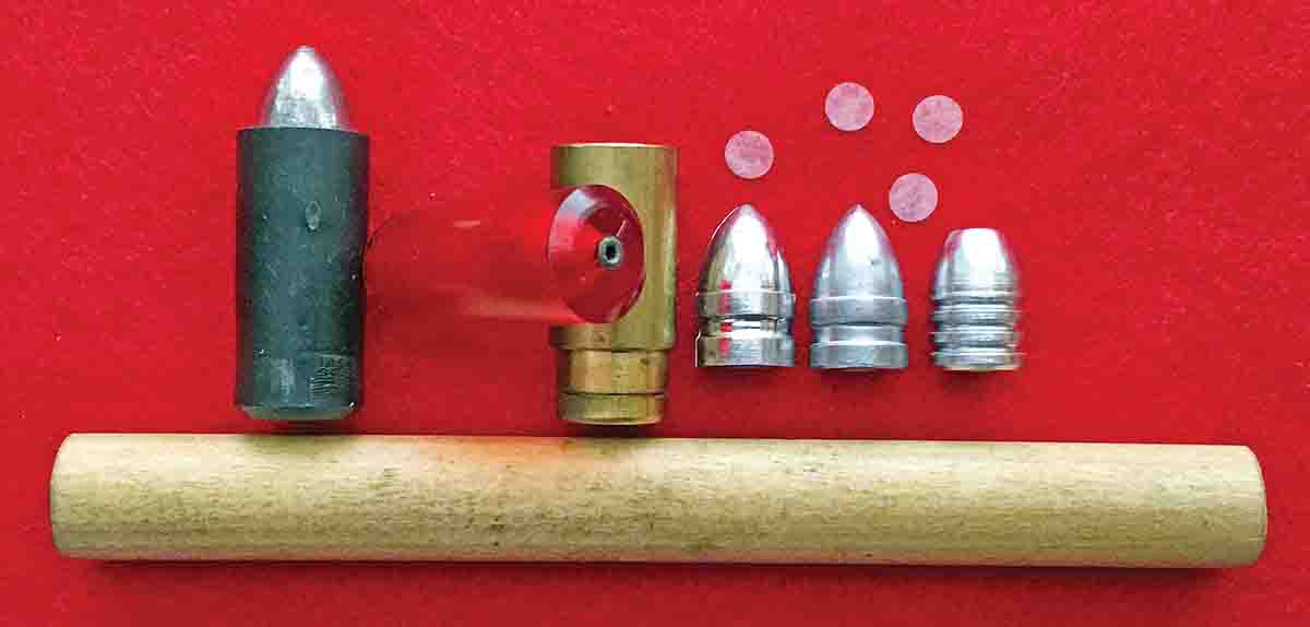 On the left is a loaded cartridge as used in this test. Next, is a soft-red rubber case with a brass insert in the touchhole to prolong the life of the case. The full-length brass case is next. The first naked bullet is the Rapine .515370, which was used in the test, and next is the Eras Gone bullet. The third bullet is the flatnose Lyman .515390 bullet. On top are the tissue paper circles used to prevent powder leaks and on the bottom is the wooden finger-lifter assist tool.